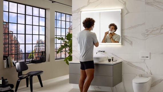 Mężczyzna goli się przy umywalce z meblami Geberit ONE i szafką z lustrem